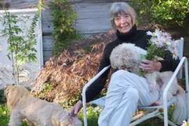 Barbara Norfleet '47, H'14 holding flowers and a dog.